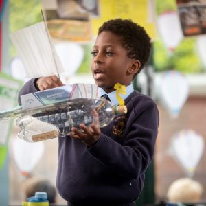 student showing off his boat made with recycled products