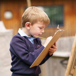 little boy holding a pencil and clipboard