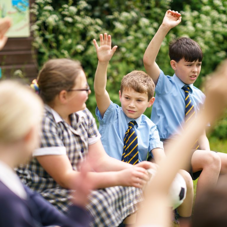 students with their hand raised in the air