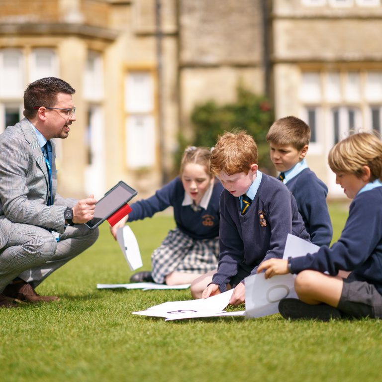 students sat on grass with their teacher