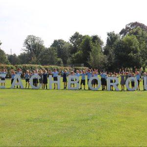 students stood behind a large sign that reads Beachborough