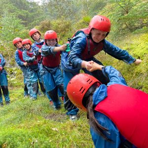 students helping each other climb up