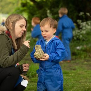 child holding a rock-made frog