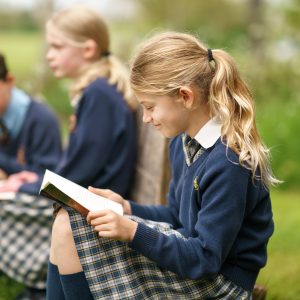 students sat on the grass reading books