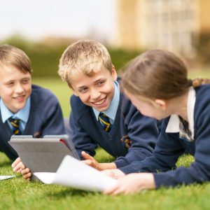 students lying on the grass and doing work