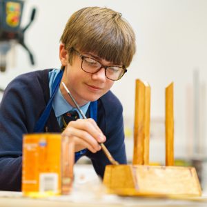 student adding varnish to wood