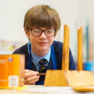 student applying solution to a piece of wood