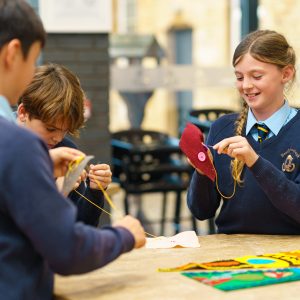 student sewing pieces of felt together