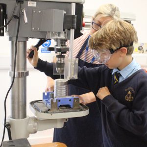 student using a drill machine to add holes to a tin can