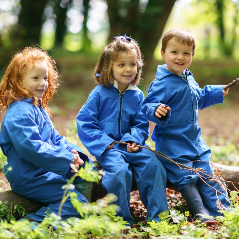3 children holding sticks and wearing blue boilersuits