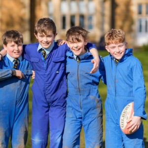 Boys supporting each other playing rugby at breaktime